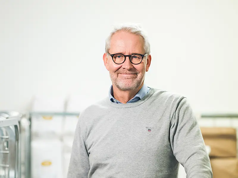 Jonas Enström, CEO and co-owner of Skafferi Värmland, wearing a grey sweater and black glasses, smiles into the camera