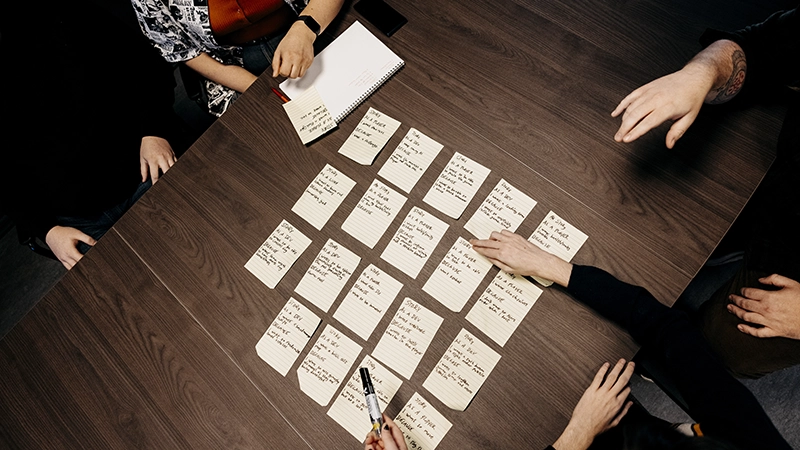 Sorterar lappar med text på, på ett bord.