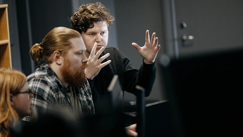 Kille gestikulerar framför en dator.