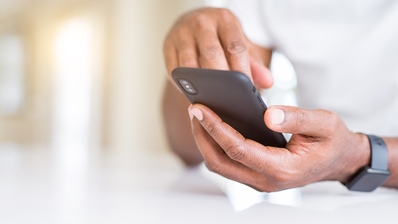 närbild på händer som håller i och skriver på en mobiltelefon