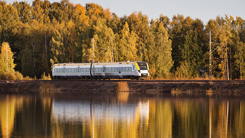 Tåg i höstlandskap vid sjö.