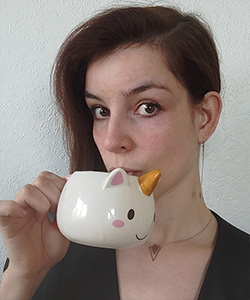 Porträttbild av Claire Denaux som håller upp en enhörningskopp.