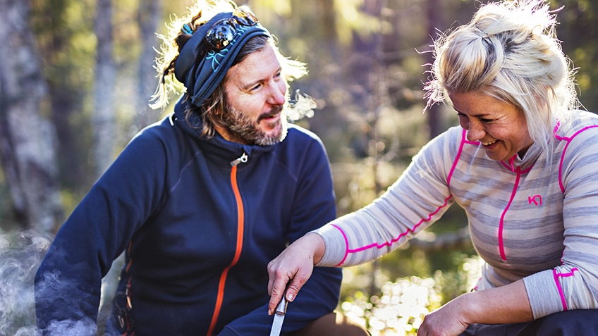 En man och kvinna i friluftskläder sitter i skogen.