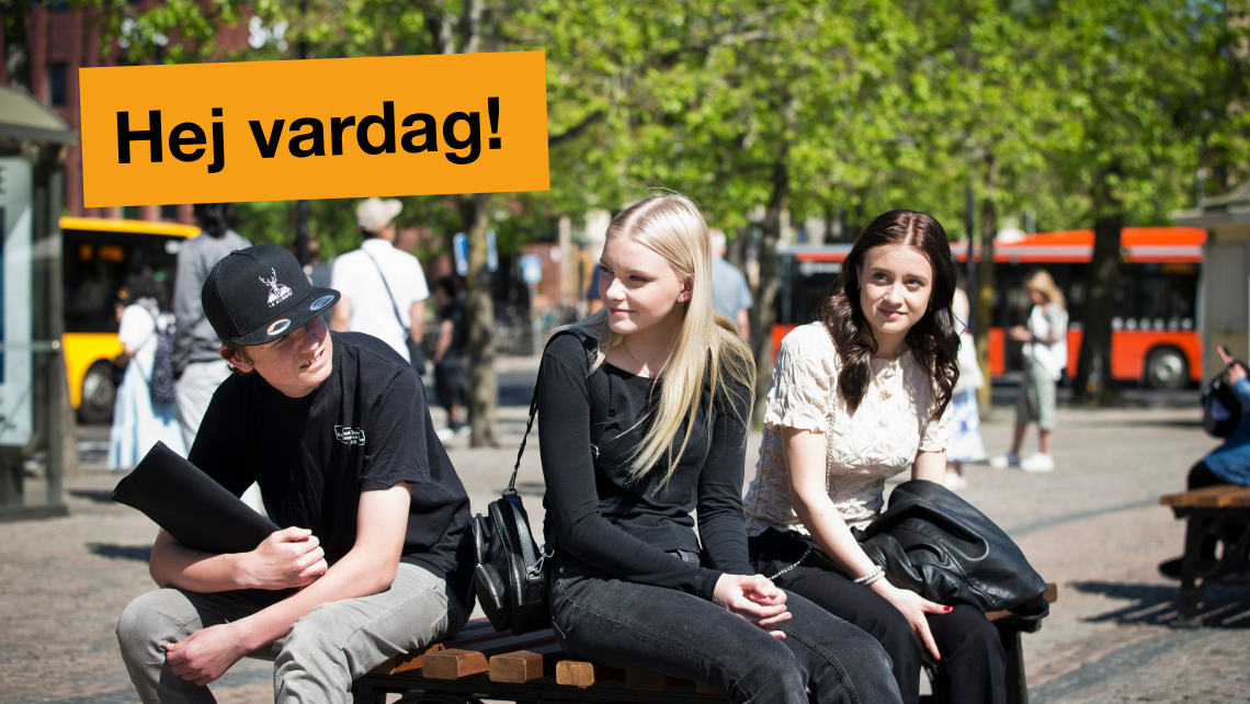 Två tjejer och en kille sitter på Stora torget och väntar på bussen, det åker bussar i bakgrunden. 