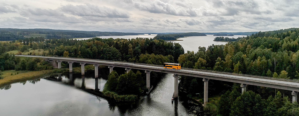 Buss åker på bro över vatten och skog