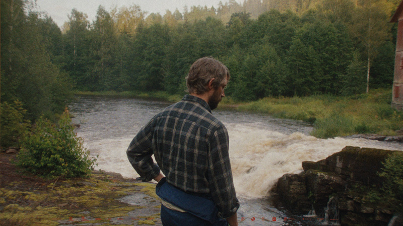 En man i en skog vid en fors.