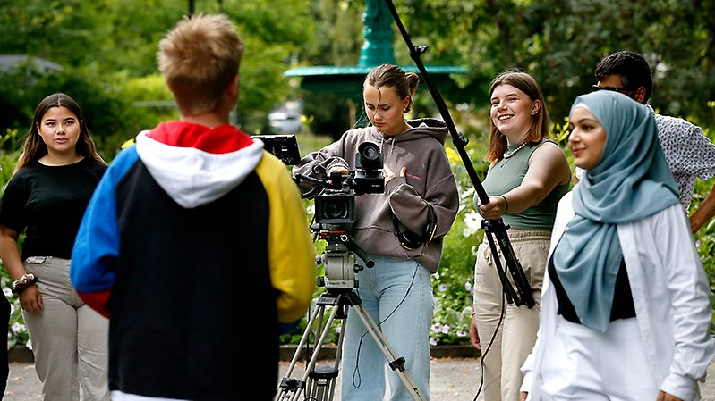 Sommarjobbar filmar i en park.